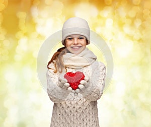 Dreaming girl in winter clothes with red heart
