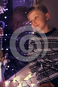 Dreaming little boy on the windowsill with Christmas Lites