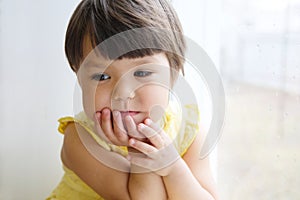 Dreaming little girl portrait leans on elbows on window longing for something. smiling child thinking about pleasing thought