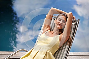 Dreaming of the perfect vacation. A pretty woman relaxing on a deck chair with her eyes closed.