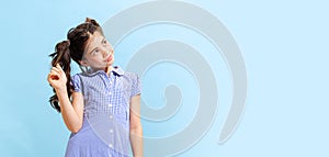 Portrait of winsome little girl,school age kid in summer dress isolated over blue background. Concept of children