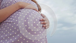 Dreaming pregnant woman in field on background of beautiful clouds