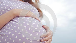 Dreaming pregnant woman in field on background of beautiful clouds