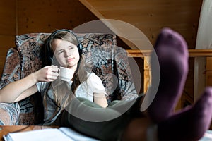 Dreaming teen girl sits with a cup in hand during break in school online webinar
