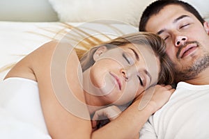 Dreaming together. Attractive young couple fast asleep together in bed.