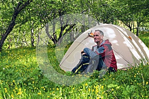 Dreaming traveler sits next to the tent