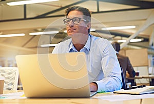 Dreaming up an new business plan. a hardworking businessman using his laptop at his desk in the office.