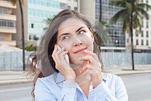 Dreaming woman in a blue blouse at phone at city