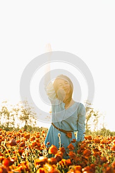 Dreaming woman enjoying of sunny day in poppy meadow.