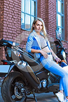 Dreaming Young Sensual Sexy Caucasian Female Biker in Blue Casual Suit With Half-Face Helmet While Standing in Front of Shiny New
