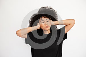 Dreaming young woman with closed eyes covering her ears with hands