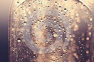 Dreamlike abstract water drops on glass bottle with light spheres in sunlight