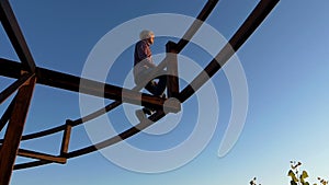 Dreamlike man sits on a metallic construction at sunset in slo-mo