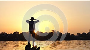 Dreamlike man stands on tree roots on a lake bank