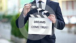Dreams come true phrase on clapperboard in hands of producer, cinematography