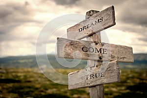 Dreams come true wooden signpost outdoors in nature.