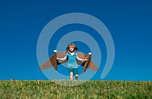 Dreams of travel. Child flying on jetpack with toy airplane on sky background. Happy child playing in cardboard plane