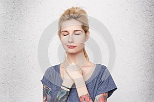 Dreams will come true! Portrait of young attractive blonde woman with pierced nose closed her eyes and dream about new life.