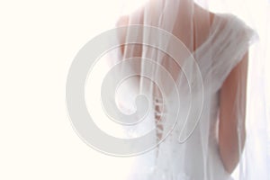 Dreamy abstract and blurry background of beautiful bride with wedding dress, from behind