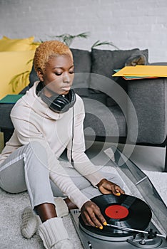 Dreamy african american woman sitting on carpet