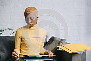 Dreamy african american woman sitting on sofa