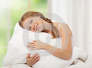 Dreamy beauty girl hugging pillow while in bed