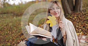 Dreamy blonde reading book in autumn park