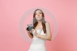 Dreamy bride woman in wedding dress looking up holding retro vintage photo camera choosing staff, photographer