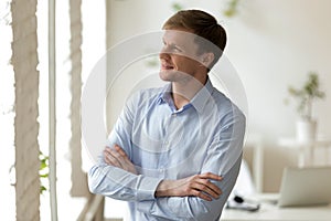 Dreamy businessman looking outside window at office.