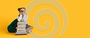 Dreamy Cute Schoolgirl In Eyeglasses Sitting At Book Stack Over Yellow Background