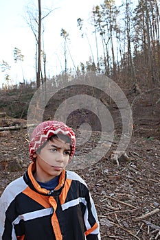 Dreamy facial expression. Autistic child looking sideways. Against the background of a felled part of the forest.