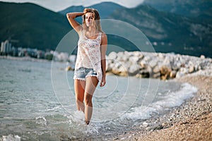 Dreamy fashion girl walk on beach with mountains background