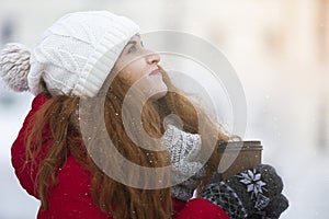 Dreamy girl with cup of coffee looking up in sky