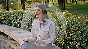 Dreamy girl reading novel sitting park bench absorbed in calm hobby closeup. photo