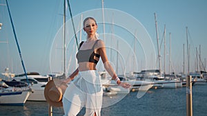 Dreamy lady relaxing quay summer evening holding straw hat. Elegant woman posing