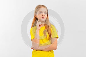 Dreamy nice pretty teen girl touch chin, thought choose decide solve problems dilemmas, wears yellow tshirt. Indoor studio shot on