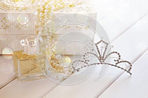 Dreamy photo of pearls necklace, tiara and perfume bottle