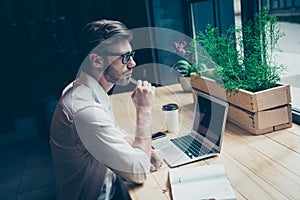 Dreamy ponder young man in formal wear is sitting at his work pl