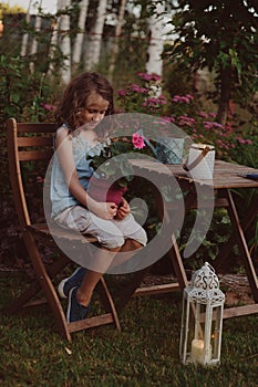 Dreamy romantic kid girl relaxing in evening summer garden