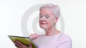 Dreamy Senior adult Woman Writing in Notebook on White Background