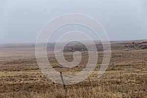 Dreamy shot of rocky hills with plateaus in open yellow field in New Mexico on cloudy day