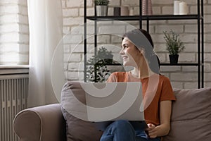 Dreamy smiling female teenager distracted from laptop screen take break