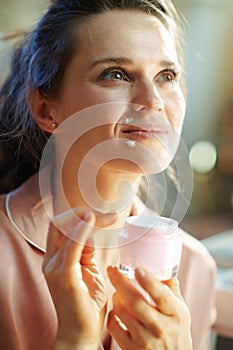 Dreamy stylish woman with jar applying lip contour cream