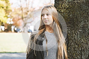 Dreamy teenage girl leaning against tree
