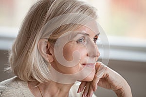 Dreamy thoughtful mature woman relaxing hoping thinking of happy