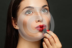 Dreamy woman face with red glossy lips and lipstick on black background