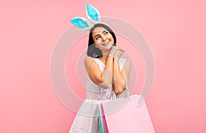 Dreamy woman in rabbit ears with shopping bags in her hands, spring shopping, traditional holiday