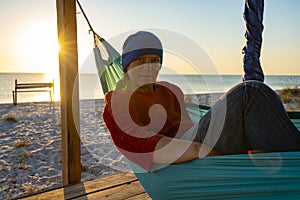 Dreamy woman relaxes in a hammock on abandoned bungalow