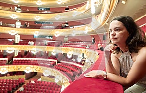 Dreamy woman sitting on balcony in theater hall during intermission