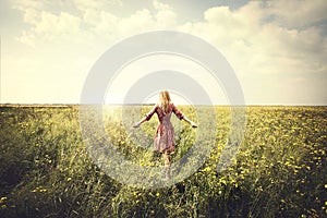 Dreamy woman walking in nature towards the sun